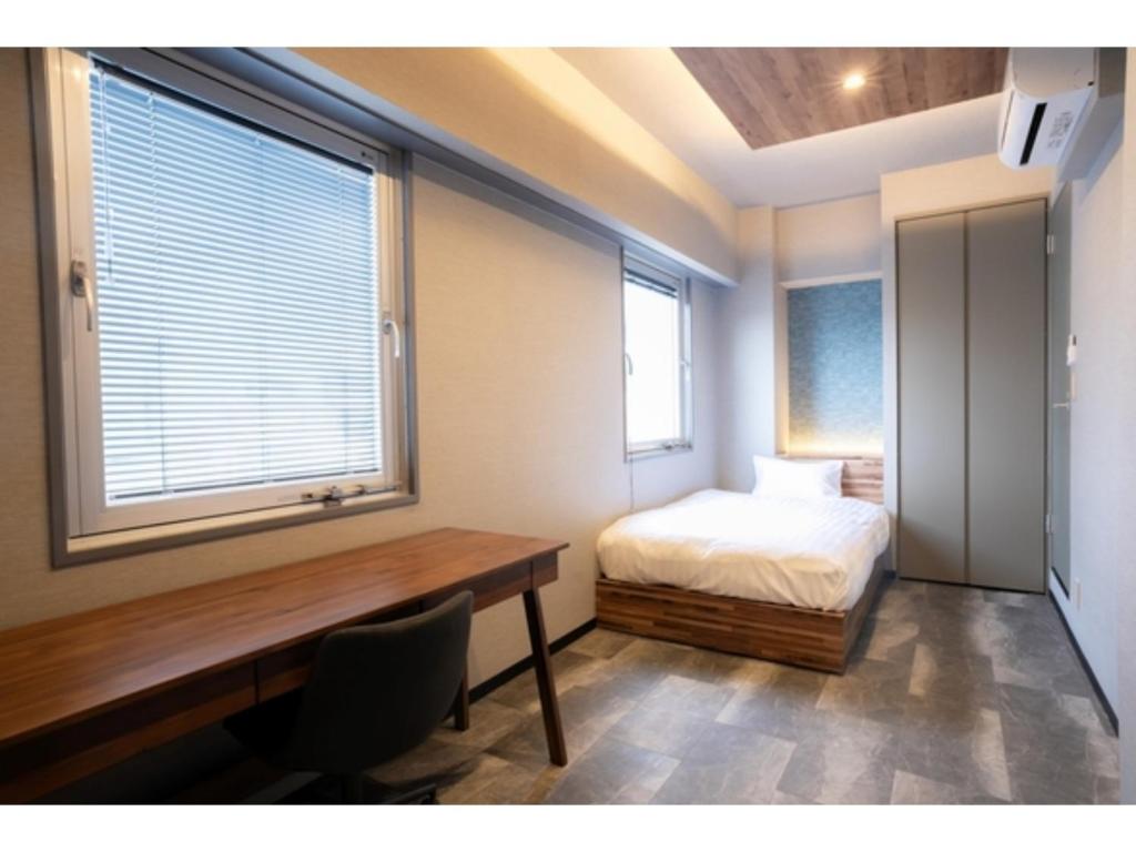 a bedroom with a bed and a desk and a window at Pin pon hotel & cabin Tokuyama Ekimae - Vacation STAY 86396v in Shunan