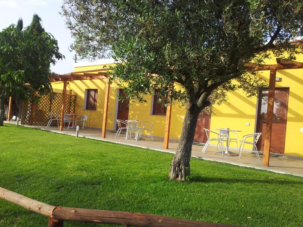 un edificio amarillo con mesas y un árbol en el césped en Il Frutteto, en Sant' Isidoro