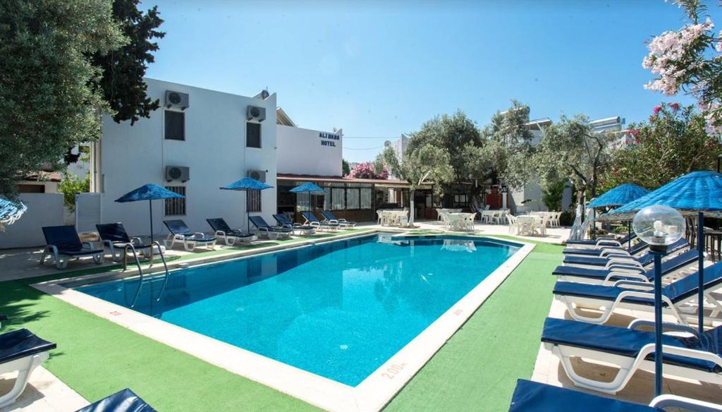 a swimming pool with chairs and umbrellas next to a building at Ali Baba Hotel Gümbet in Gümbet