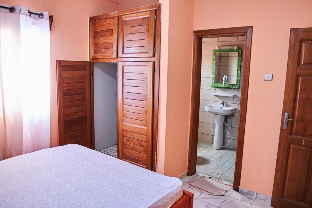 a bedroom with a door leading to a bathroom with a sink at Appartements et studios meublés kahak in Douala