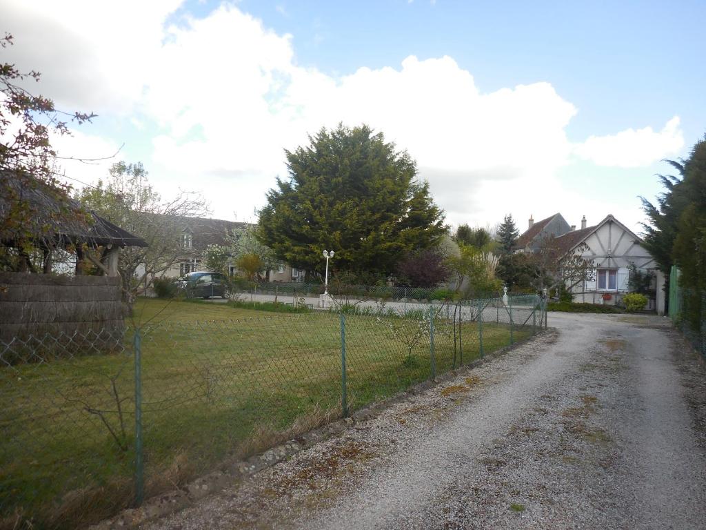 a fence on a dirt road next to a field at Les rouches in Cormeray