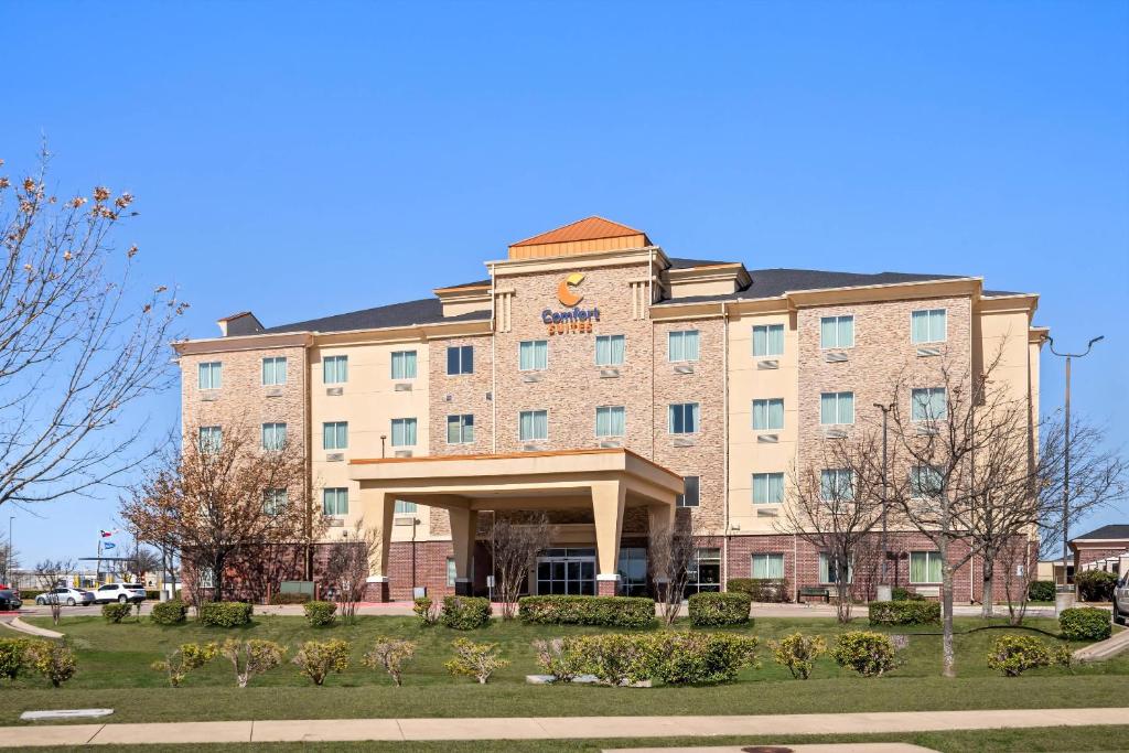 a large brick building with a sign on it at Comfort Suites Waxahachie - Dallas in Waxahachie