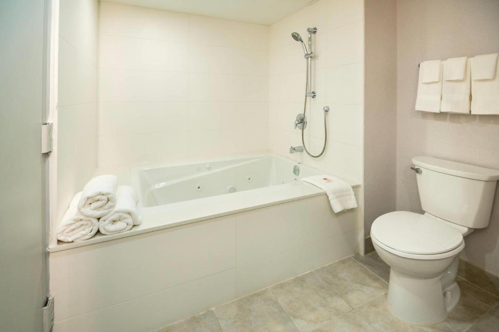 a white bathroom with a toilet and a bath tub at Comfort Inn & Conference Centre Toronto Airport in Toronto