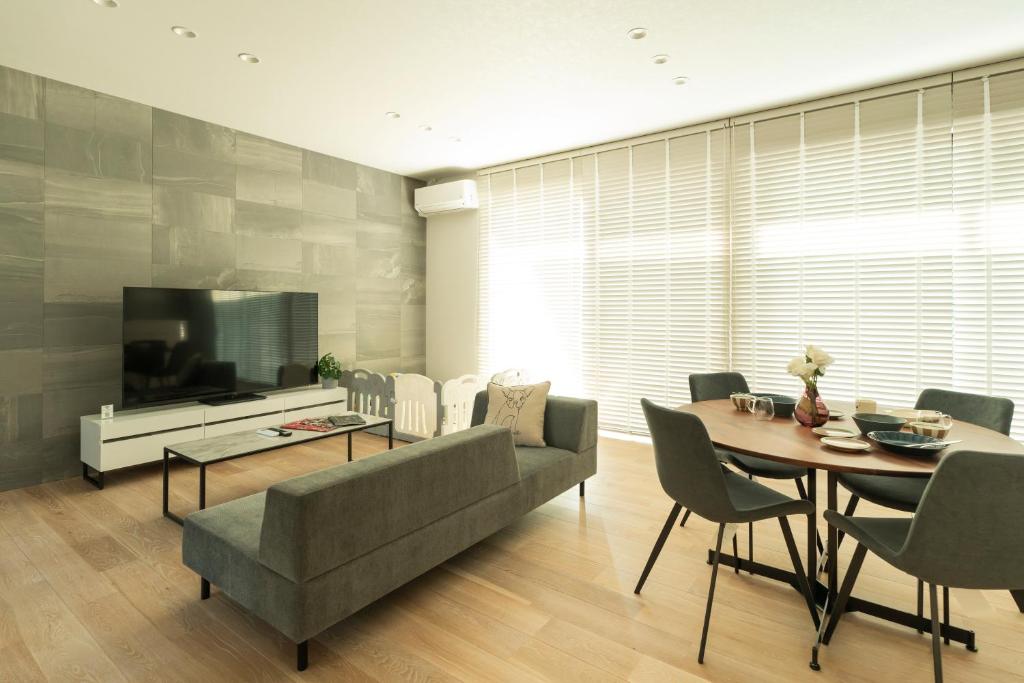 een woonkamer met een bank, een tafel en een televisie bij -Mova Villa Koshi Daiwa 2-近阿蘇 熊本城 各類溫泉 台積電 合志獨棟民宿 體驗當地生活 in Yuge