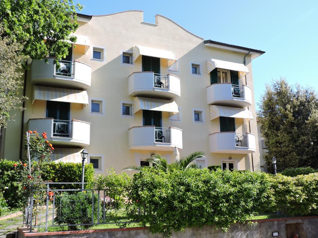 un gran edificio de apartamentos con balcones y arbustos en Hotel Il Pino, en San Vincenzo