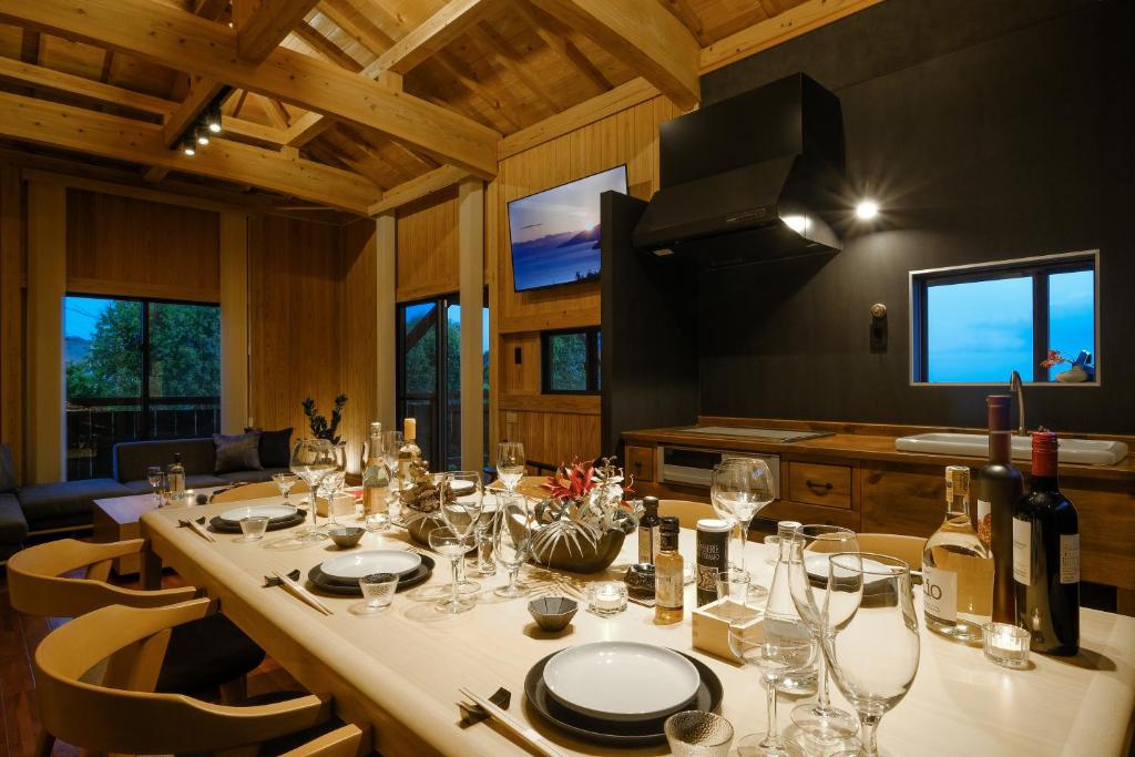 ein Esszimmer mit einem langen Tisch mit Weingläsern in der Unterkunft オーシャンビュー BBQ可 最大8名 自然を満喫できる宿 Maru in Motobu