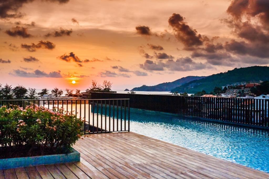 a wooden deck with a sunset over a body of water at The Deck Condominium by Lofty in Patong Beach
