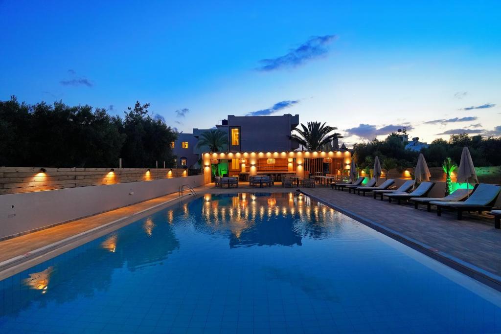 a large swimming pool with chairs and a building at PEARL BOUTIQUE Hotel BEACH ROAD MALIA in Malia