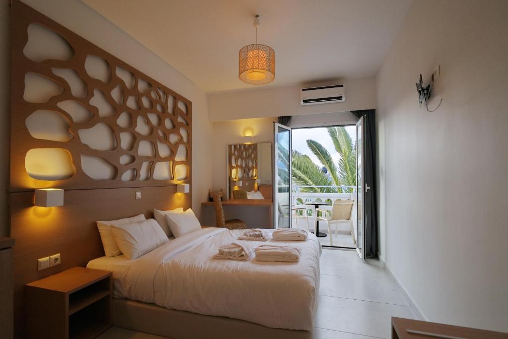Un dormitorio con una cama grande y un balcón. en PEARL BOUTIQUE Hotel BEACH ROAD MALIA, en Malia
