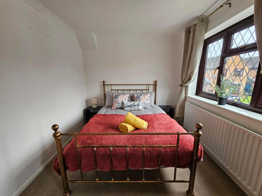 a bedroom with a bed with a red blanket and a window at Carey House Long Stays Free Parking and WI-FI in Swindon