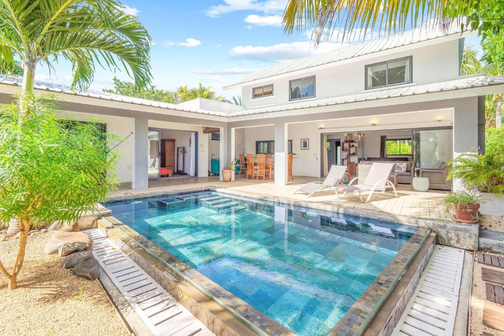 a villa with a swimming pool in front of a house at Vayu - Eco Chic House Tamarin in Tamarin