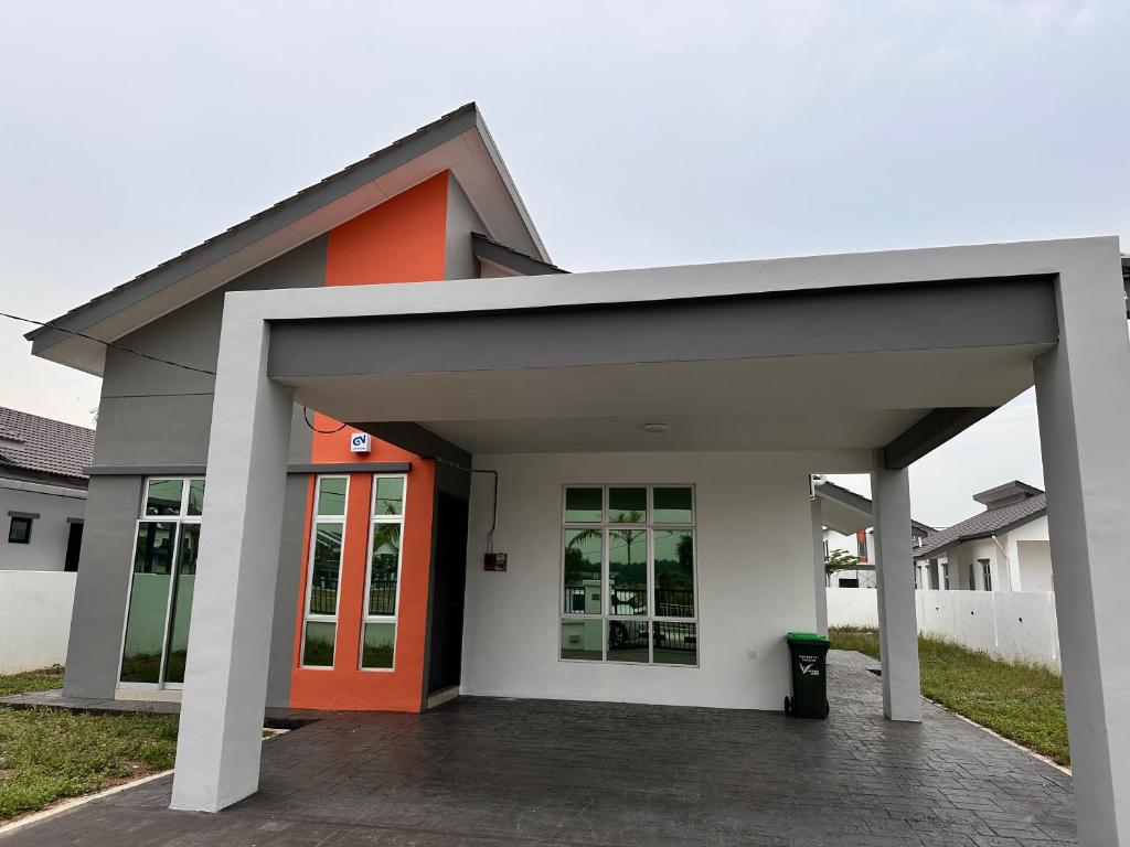 a house with an orange door in a yard at Xiang Homestay in Padang Serai