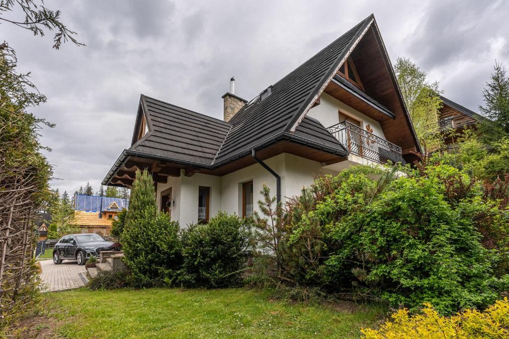 コシチェリスコにあるGolden Villa Zakopane Jacuzzi - Grill - Taras z Widokiem - Prywatny Ogródの黒い屋根の家と駐車された車