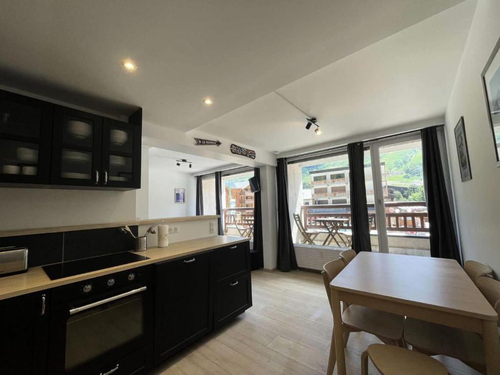 une cuisine avec des armoires noires et une table avec des chaises dans l'établissement Résidence Waala - Cosy T3 au cœur de la station face aux pistes MAE-5191, à Vénosc
