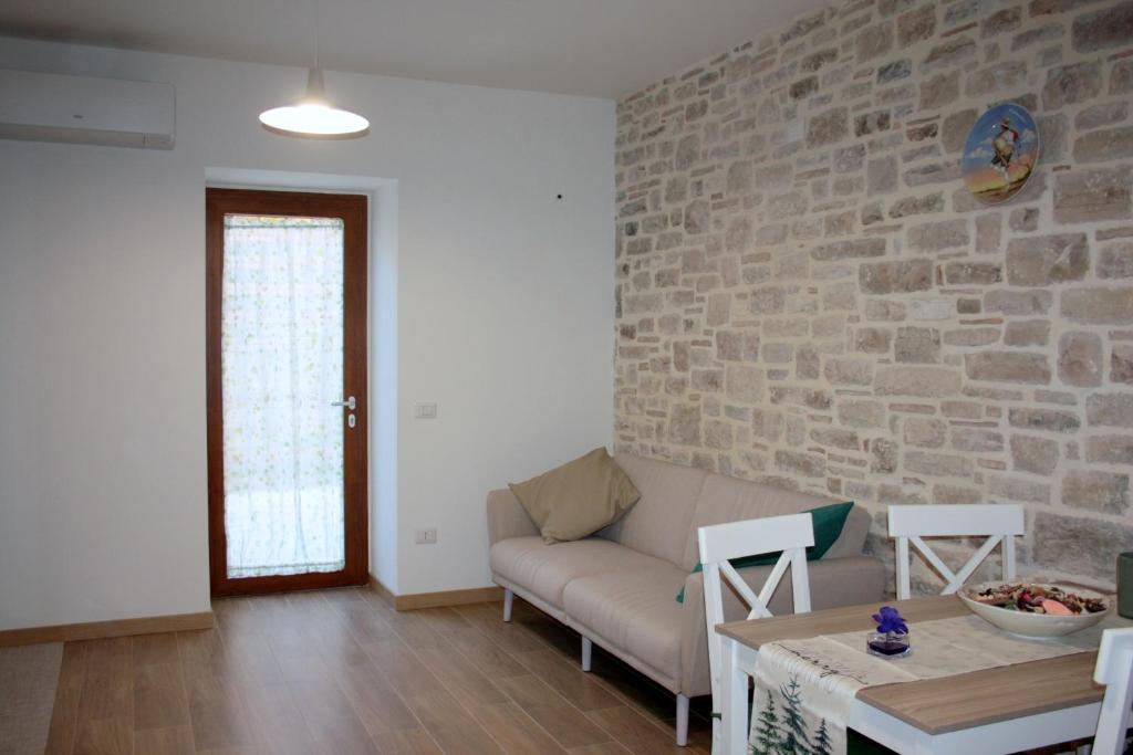 a living room with a couch and a brick wall at LA ROCCIA DI VICIDOMINI - Affittacamere in San Marco dei Cavoti