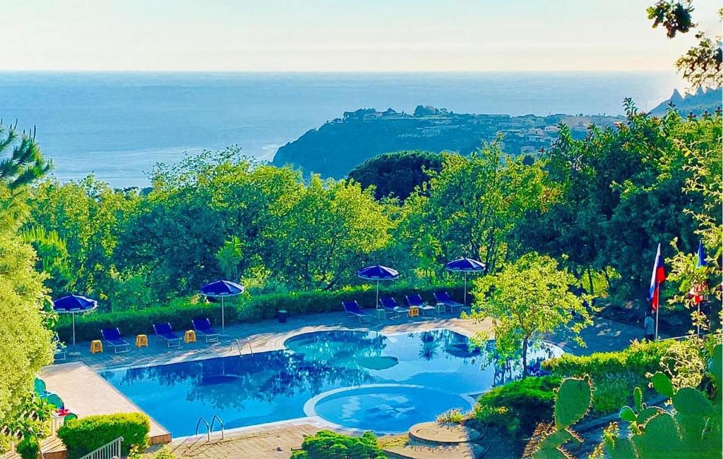 a swimming pool with umbrellas and chairs and the ocean at 1 Bedroom Lovely Apartment In Ricadi in Ricadi