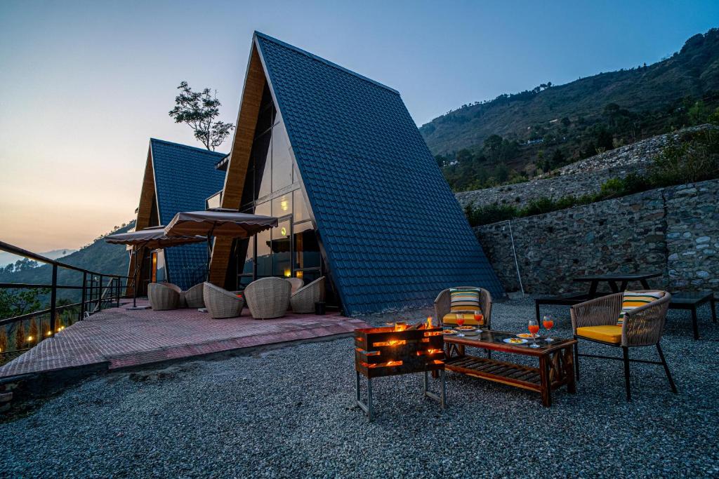 比姆塔尔Echo By The Lakes Pet-friendly Retreat by the Lake With Game Zone & Garden的蓝色屋顶的房子,配有桌椅