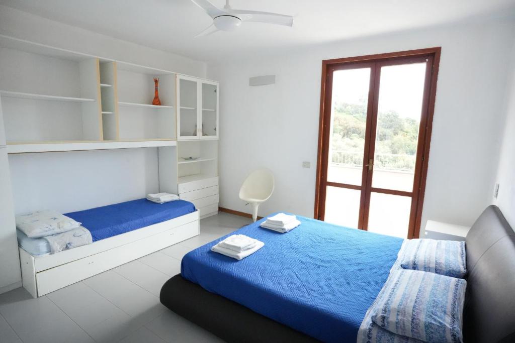 a white bedroom with a blue bed and a window at Blue Horizon Apartment- 5 Terre in Monterosso al Mare