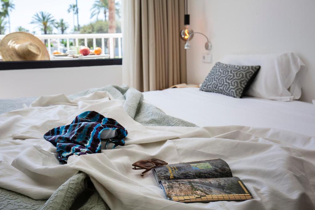a white bed with a book and sunglasses on it at Villa Miel in Cala Millor