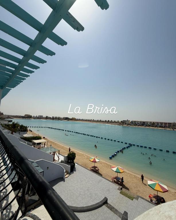a beach with umbrellas and people in the water at LA Brisa Durrat Alarous شاليهات لابريزا درة العروس شاطئ البرادايس للعوائل فقط in Durat Alarous