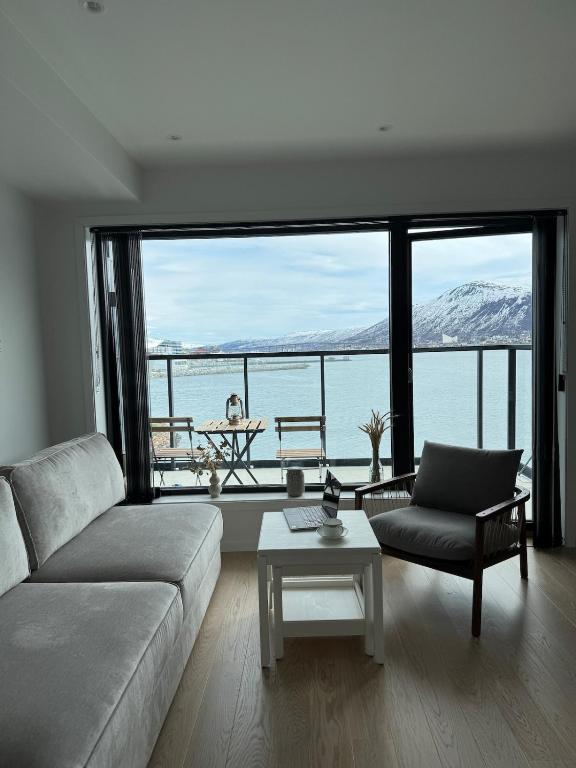 a living room with a couch and a view of the water at Wonderful apartment in centrum in Tromsø