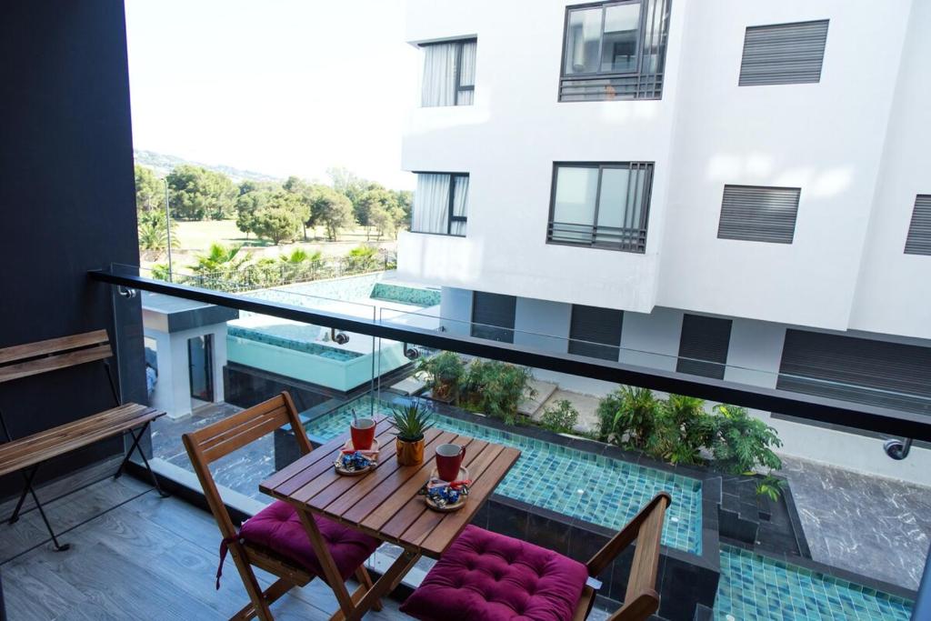 a balcony with a table and chairs and a pool at Blue Palm Pool, quiet and comfort in Tangier in Tangier