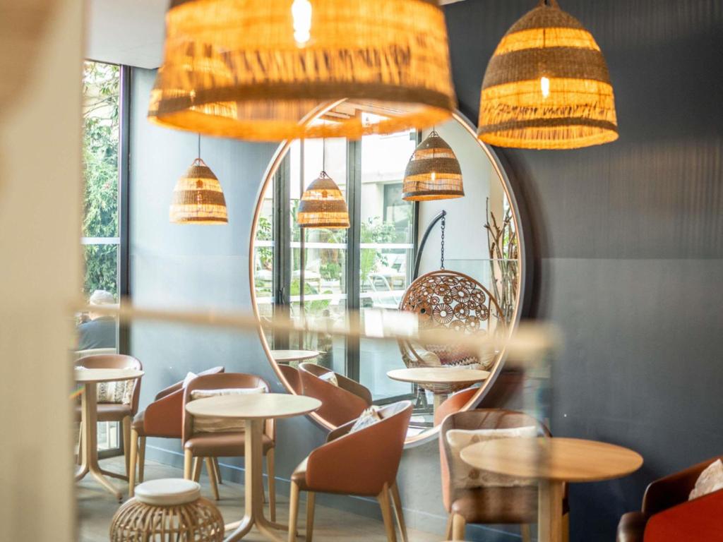 a restaurant with a mirror and tables and chairs at Croisette Beach Hotel Cannes - MGallery Collection in Cannes
