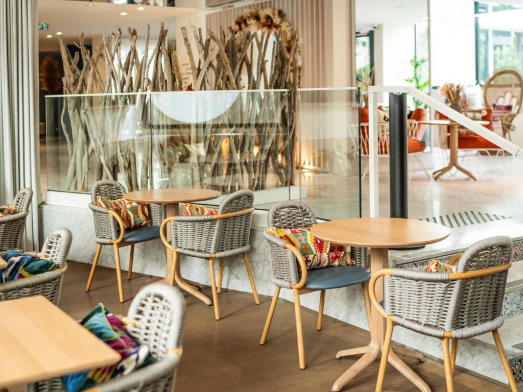 a group of tables and chairs in a restaurant at Croisette Beach Hotel Cannes - MGallery Collection in Cannes