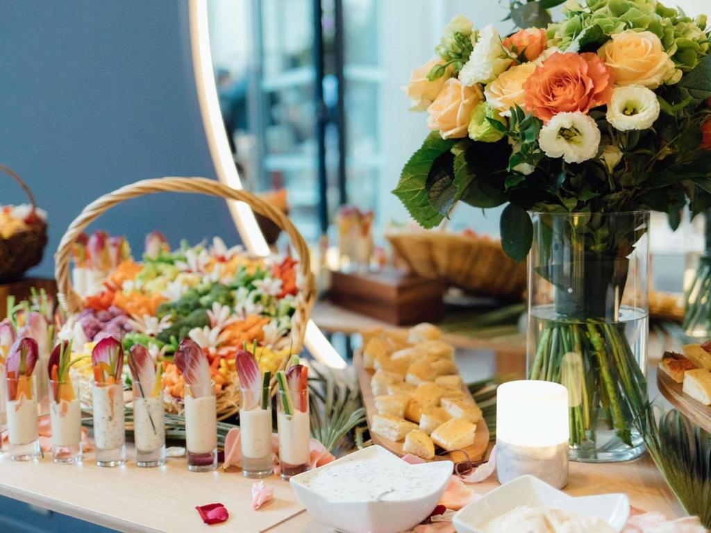 a table topped with a vase filled with flowers and a vase of food at Croisette Beach Hotel Cannes - MGallery Collection in Cannes