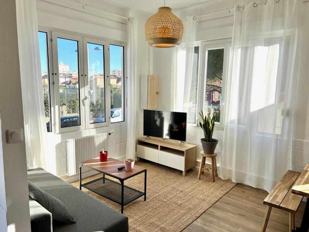 - un salon avec un canapé, une télévision et des fenêtres dans l'établissement Charmant appartement 3 chambres à 100m de la plage centrale, à Canet