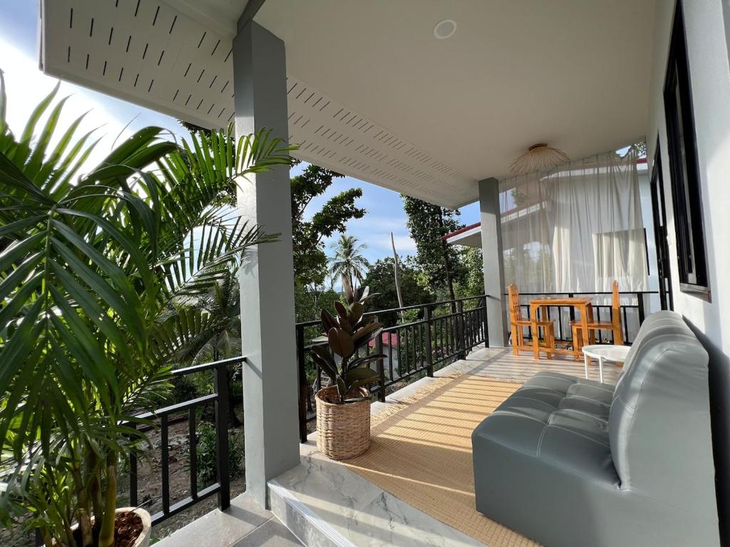 a porch with a blue couch on a balcony at Sunset Hut Haad Yao in Haad Yao