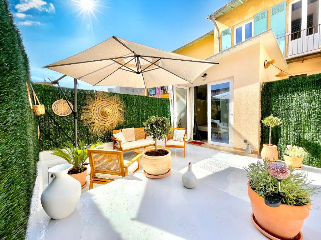 une terrasse avec une table, un parasol et des plantes en pot dans l'établissement Le Petit Nice, à Nice