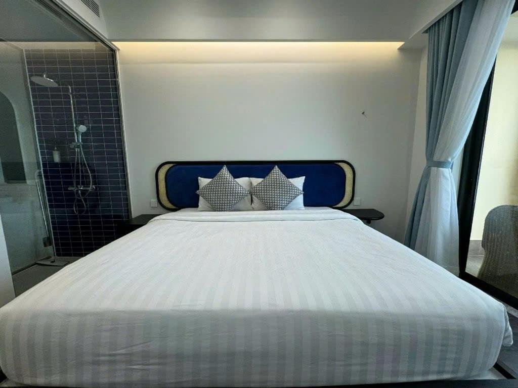 un grande letto bianco in una stanza con doccia di The Hillside a Phu Quoc