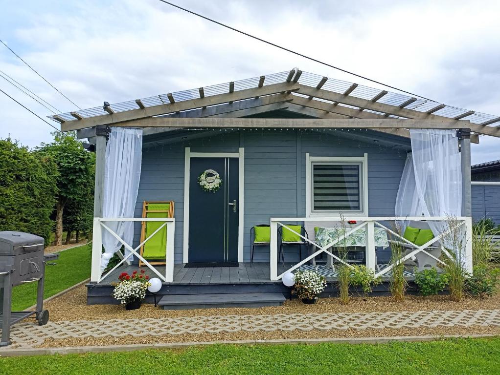 a blue house with a pergola on the porch at Domki u Ewci - Domki całoroczne in Uherce Mineralne