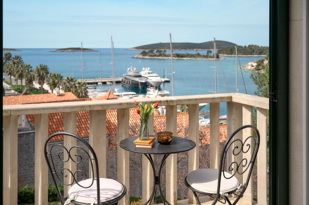 a table and chairs on a balcony with a view of a harbor at Sun Spalato Maslinica in Maslinica