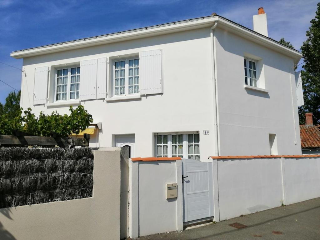 une maison blanche avec une clôture blanche dans l'établissement Maison au calme proche plage, centre à 2 min à pied, à La Tranche-sur-Mer