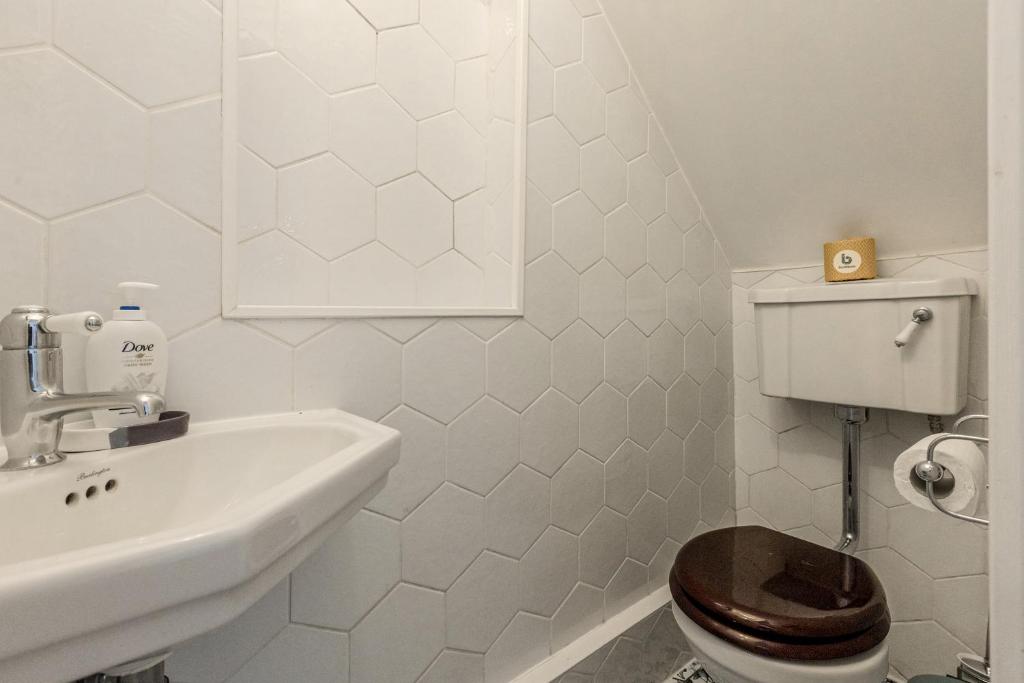 a white bathroom with a toilet and a sink at Gorgeous 2BR plus Victorian home with Parking and Garden in London