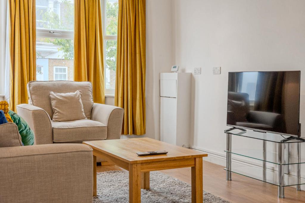 a living room with a couch and a tv and a table at Gorgeous 2BR plus Victorian home with Parking and Garden in London