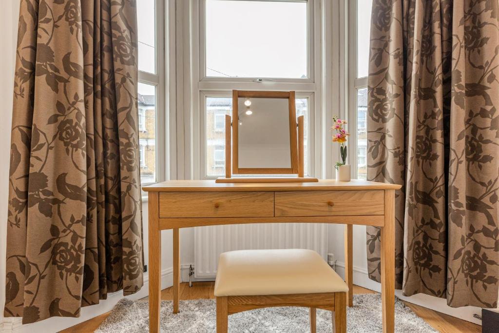 a dressing table with a mirror and a chair in a window at Gorgeous 2BR plus Victorian home with Parking and Garden in London