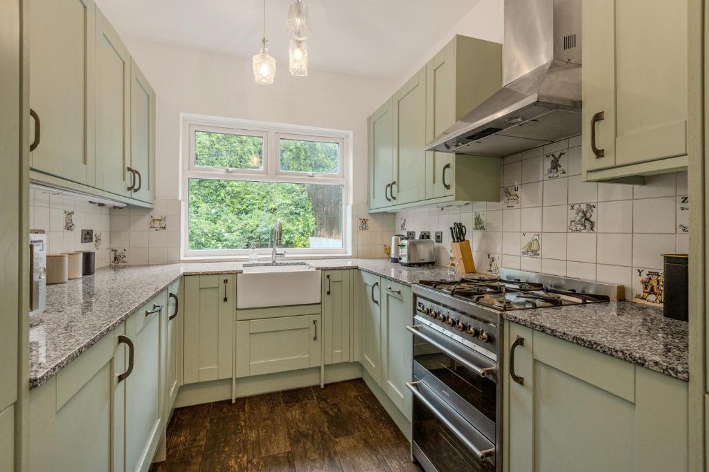 a kitchen with green cabinets and a sink at Gorgeous 2BR plus Victorian home with Parking and Garden in London