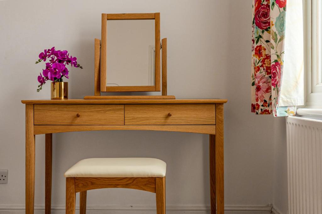 a wooden dressing table with a mirror and a stool at Gorgeous 2BR plus Victorian home with Parking and Garden in London