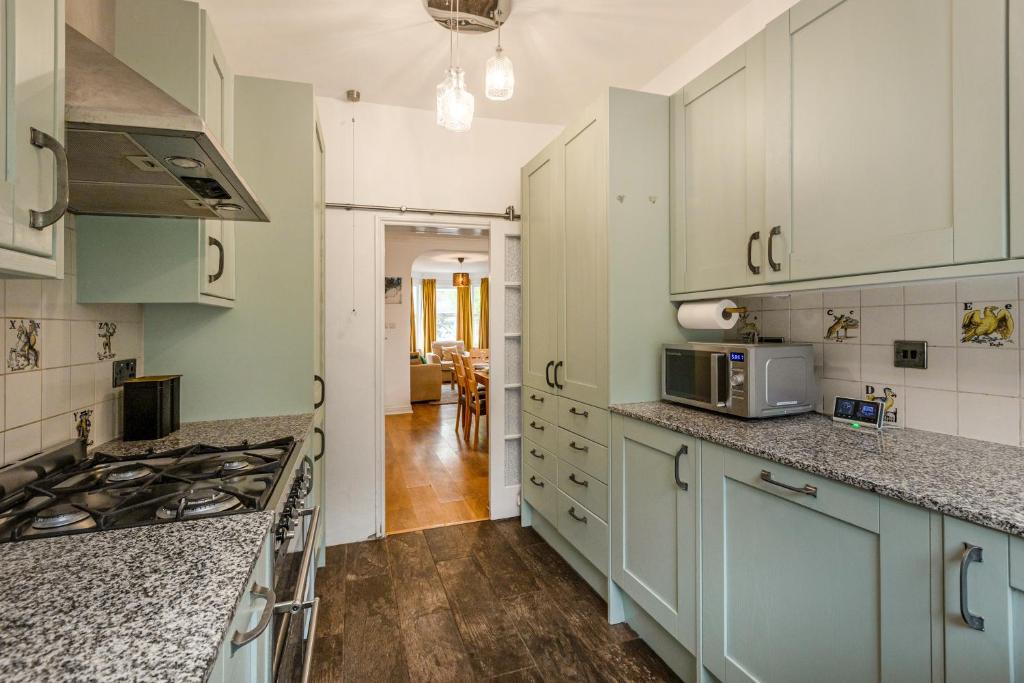 a kitchen with white cabinets and a stove top oven at Gorgeous 2BR plus Victorian home with Parking and Garden in London
