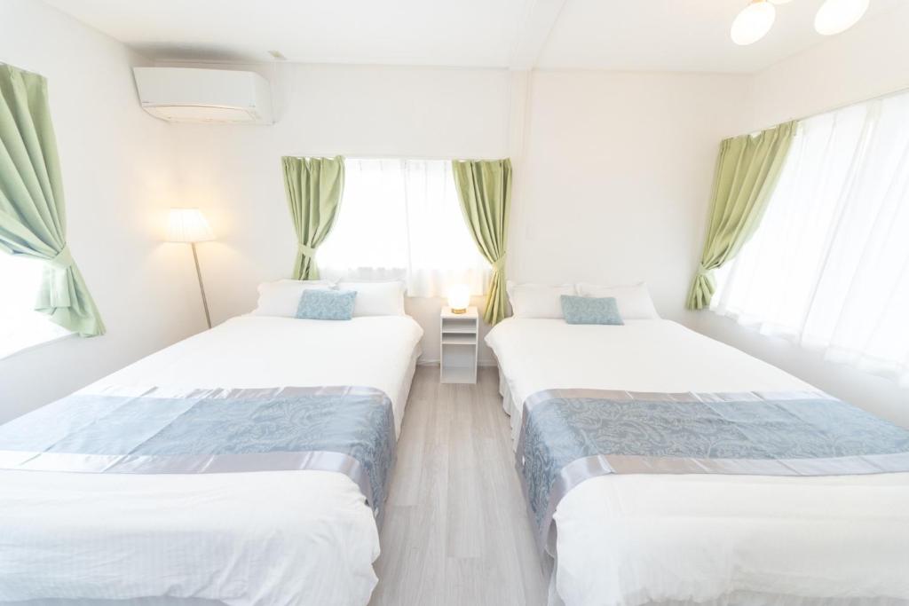 two beds in a white room with windows at Yokkaichi City - House - Vacation STAY 68977v in Nishi-hino
