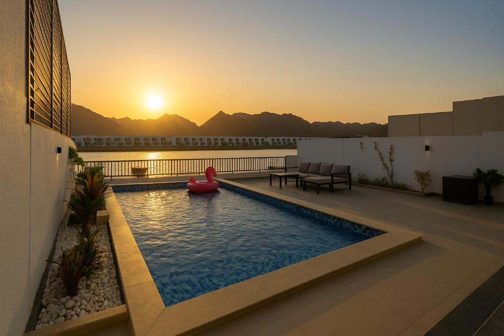 a swimming pool on the roof of a building with a sunset at Seascape Villa Marine in Fujairah