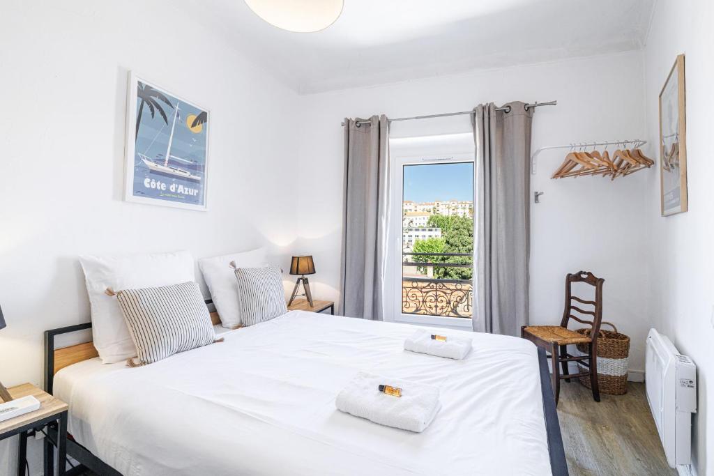 une chambre avec un grand lit blanc et une fenêtre dans l'établissement Joli appartement à côté du Palais des Festivals, à Cannes