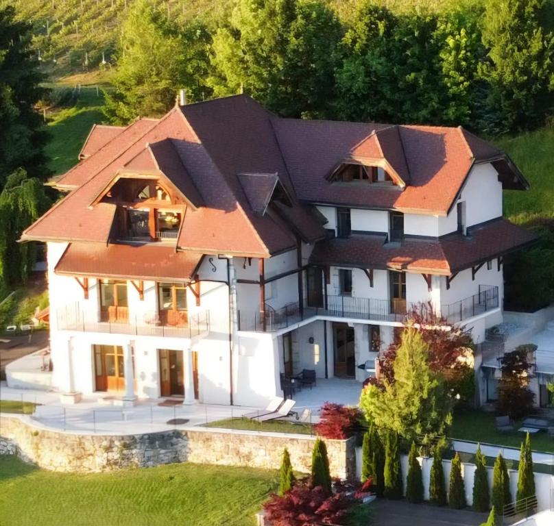 a large white house with an orange roof at Villa Savoie - luxe et sérénité- piscine et jacuzzi - vue panoramique sur le lac d Annecy in Veyrier-du-Lac