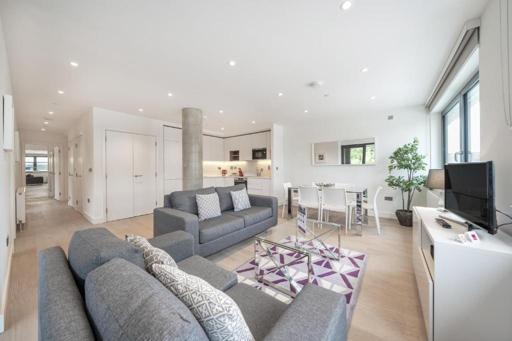 a living room with a couch and a tv and a kitchen at Roomspace Serviced Apartments -Oasis Way in London