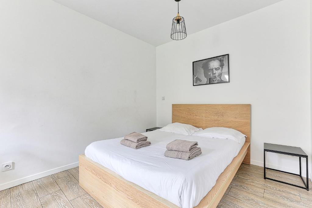 une chambre avec un grand lit blanc avec deux serviettes dessus dans l'établissement 10 minutes à pied de La Villette - 4 voyageurs, à Paris