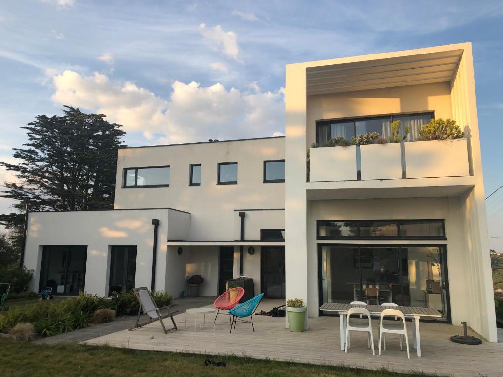 une maison avec des chaises et des tables devant elle dans l'établissement Villa de la Pointe, à Saint-Pabu