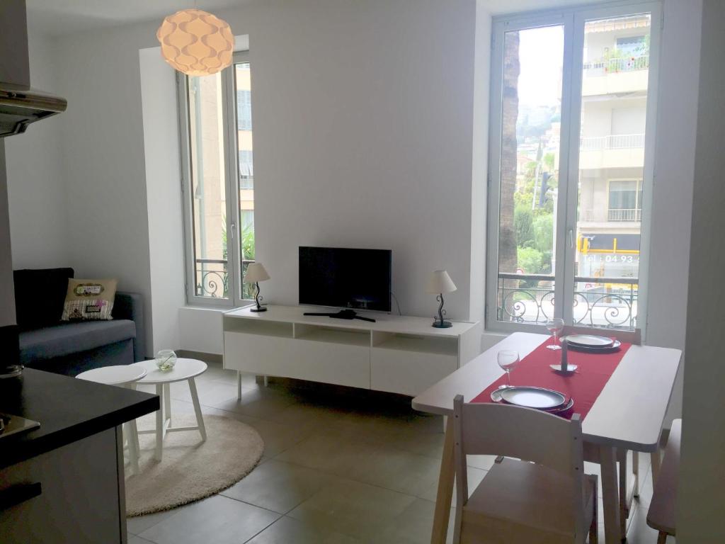een woonkamer met een televisie en een tafel en stoelen bij Le Cedre Bleu in Nice